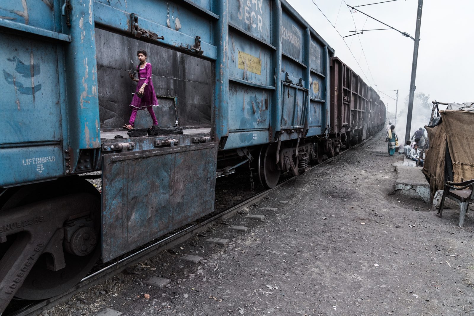 A young girl scavenges for left over coal to use as fuel from a coal transport train carraige in Madhya Pradesh