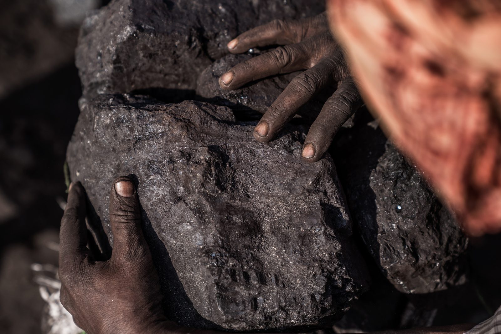 A coal miner examines a large chunk of coal