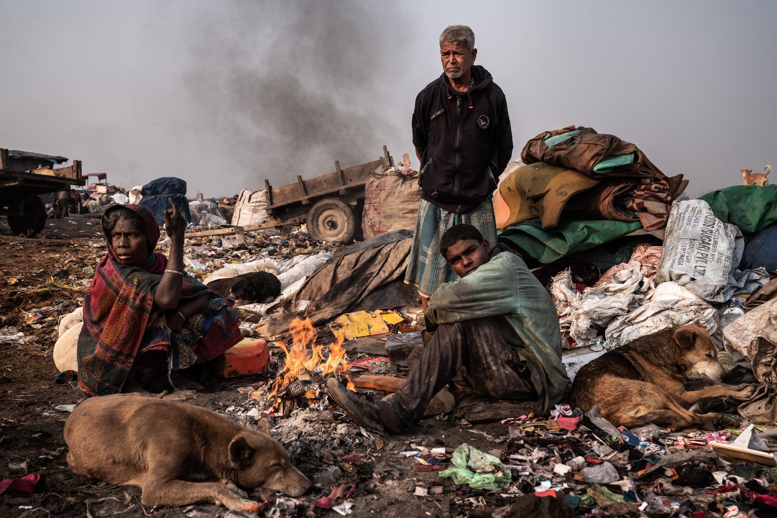 Workers at a garbage collection facility keep warm during winter by a fire.