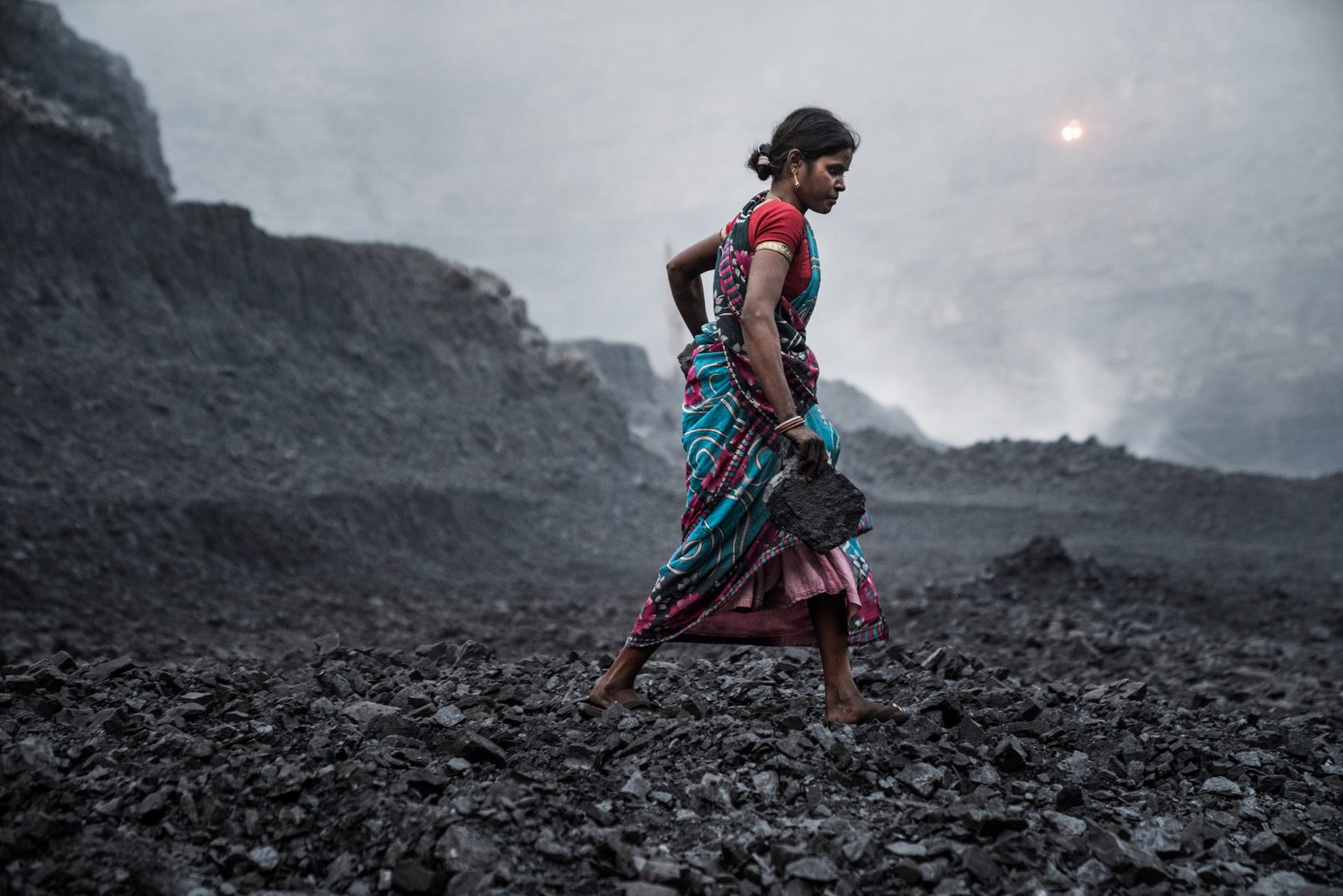 A woman scavenges for leftover coal within a mine in Jharkhand, India