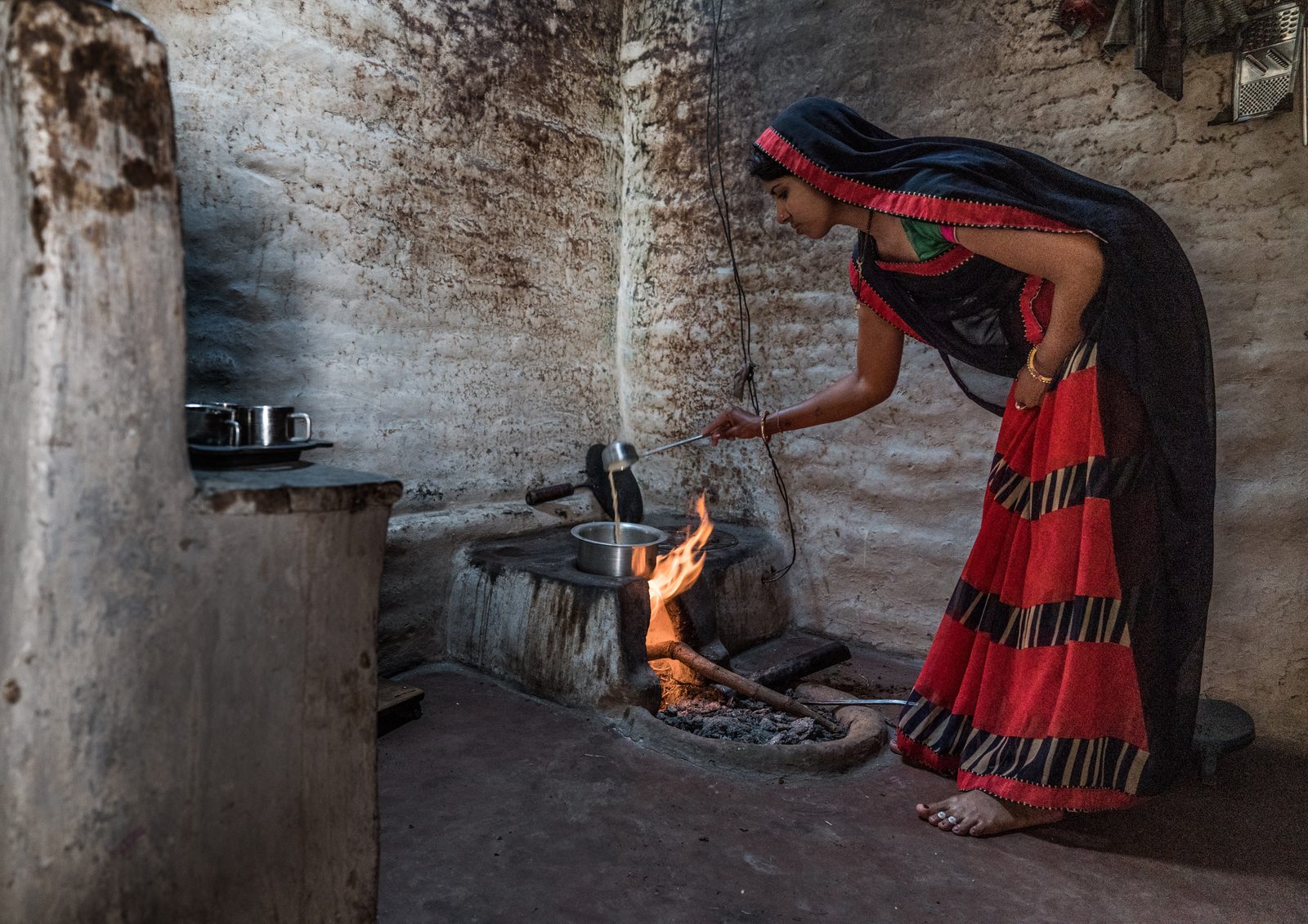 A woman prepares chai over and open fire in her rural home in Madhya Pradesh