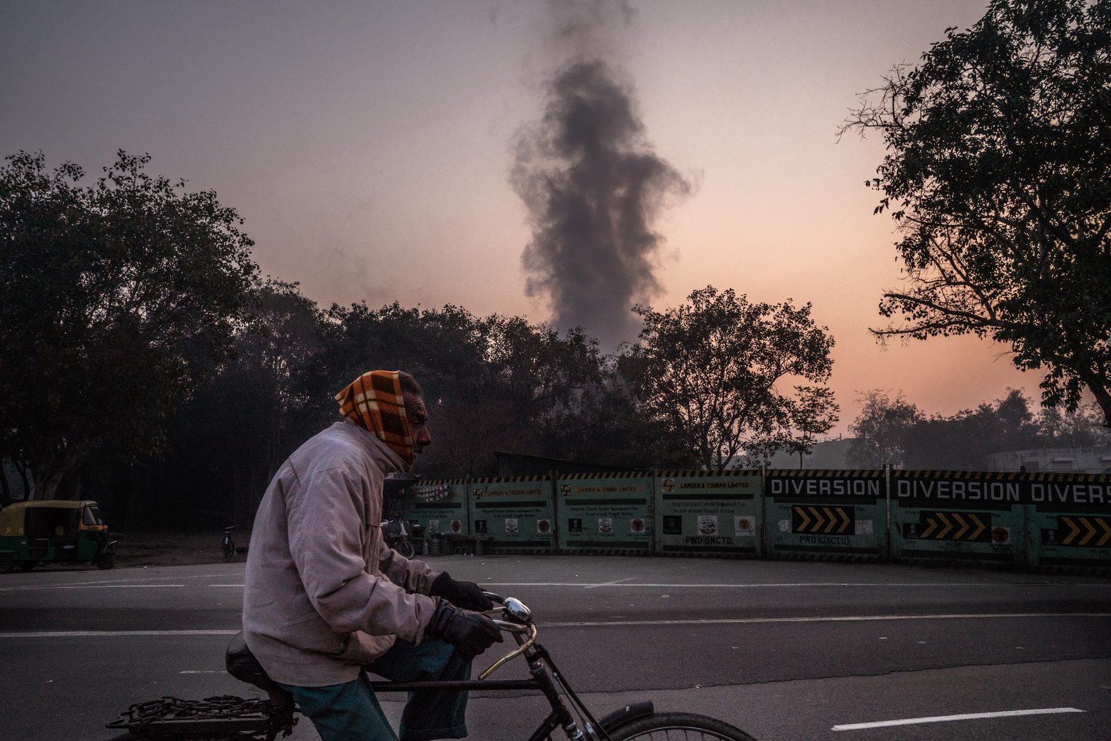 A man rides on the road as a combustion steam rises from a thermal power plant in New Delhi, India