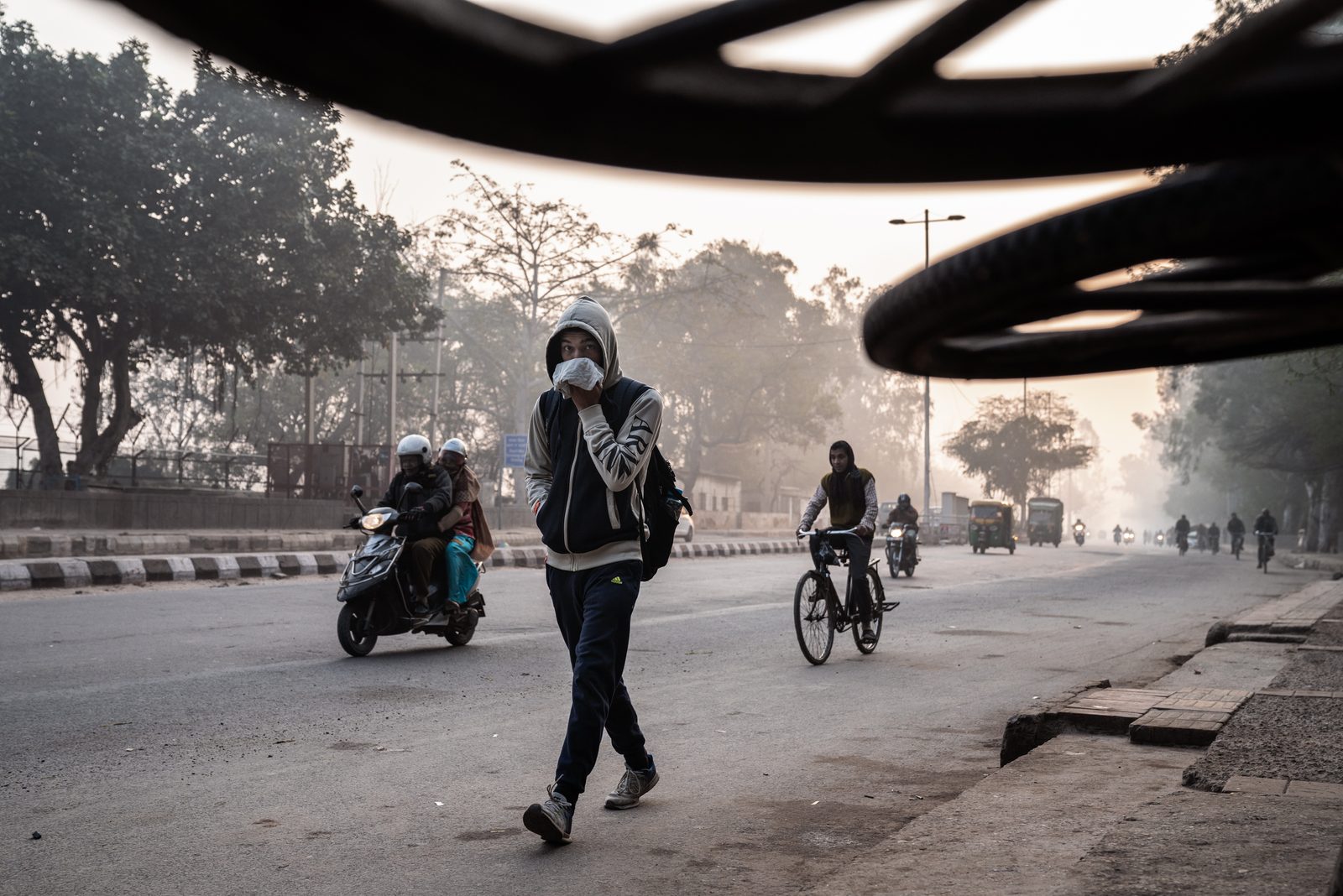 A young man covers his face from the morning smog in New Delhi, India