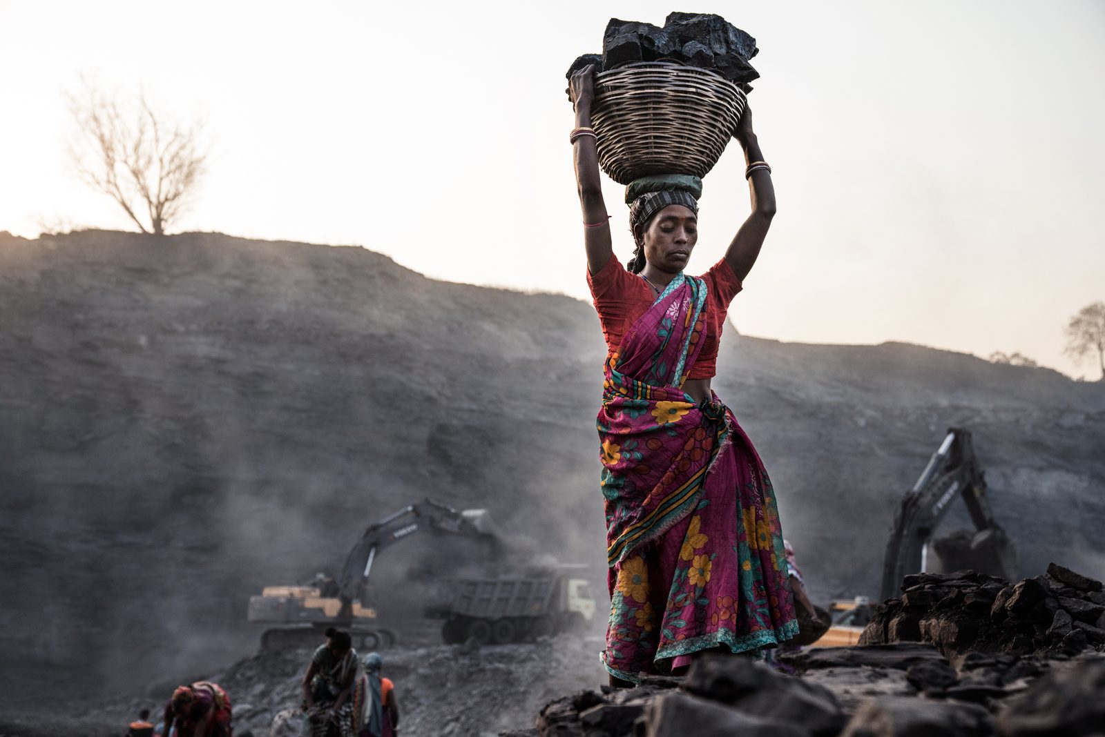 A woman carries scavenged coal out of the mine site in Jharkhand, India