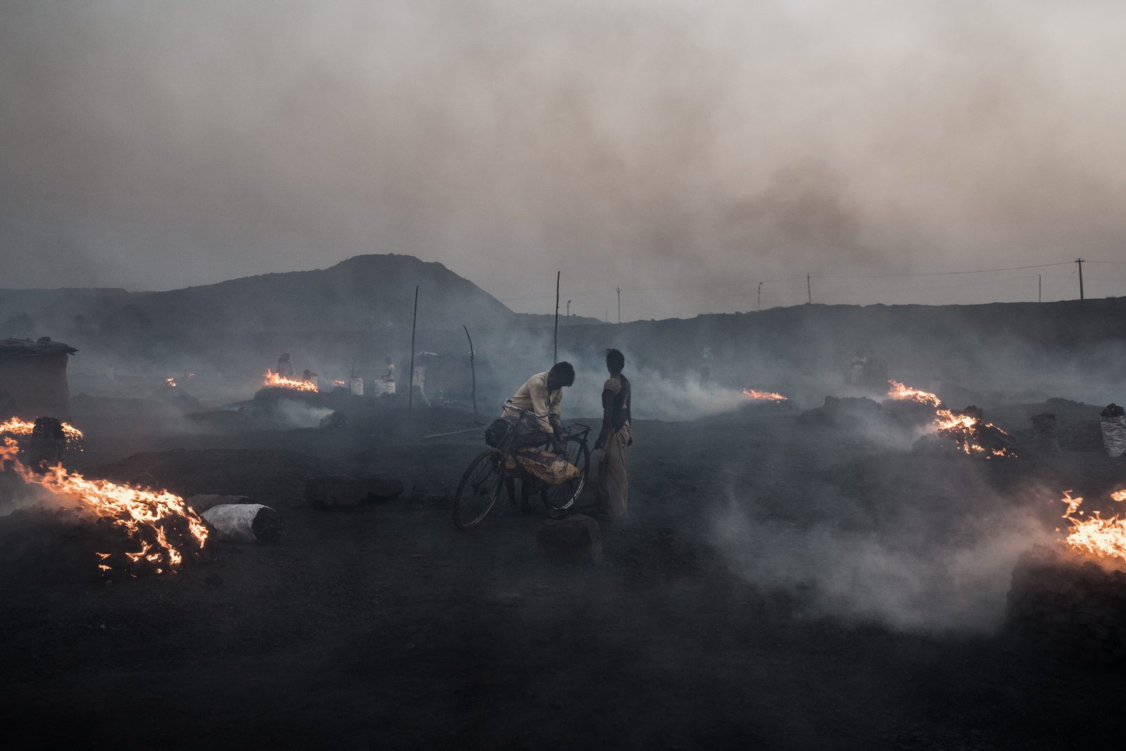 A young couple offloads scavenged coal from a nearby mine for charcoal production.