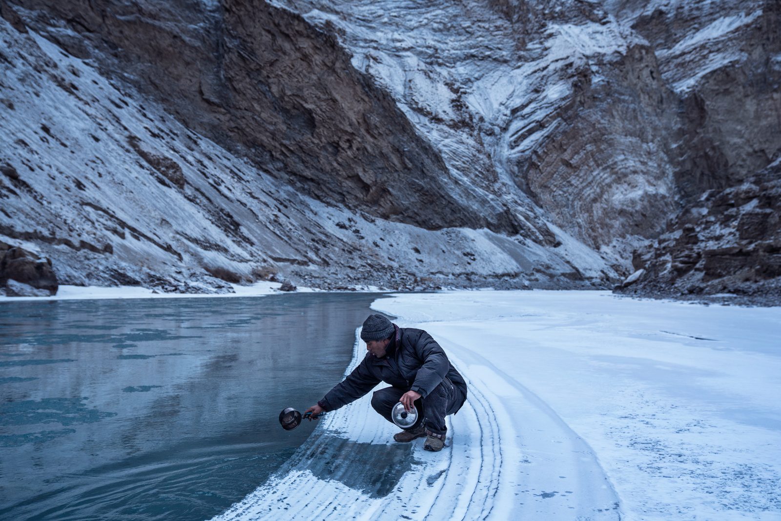 A Zanskari man washes his pan in the partly frozen Zanskar River