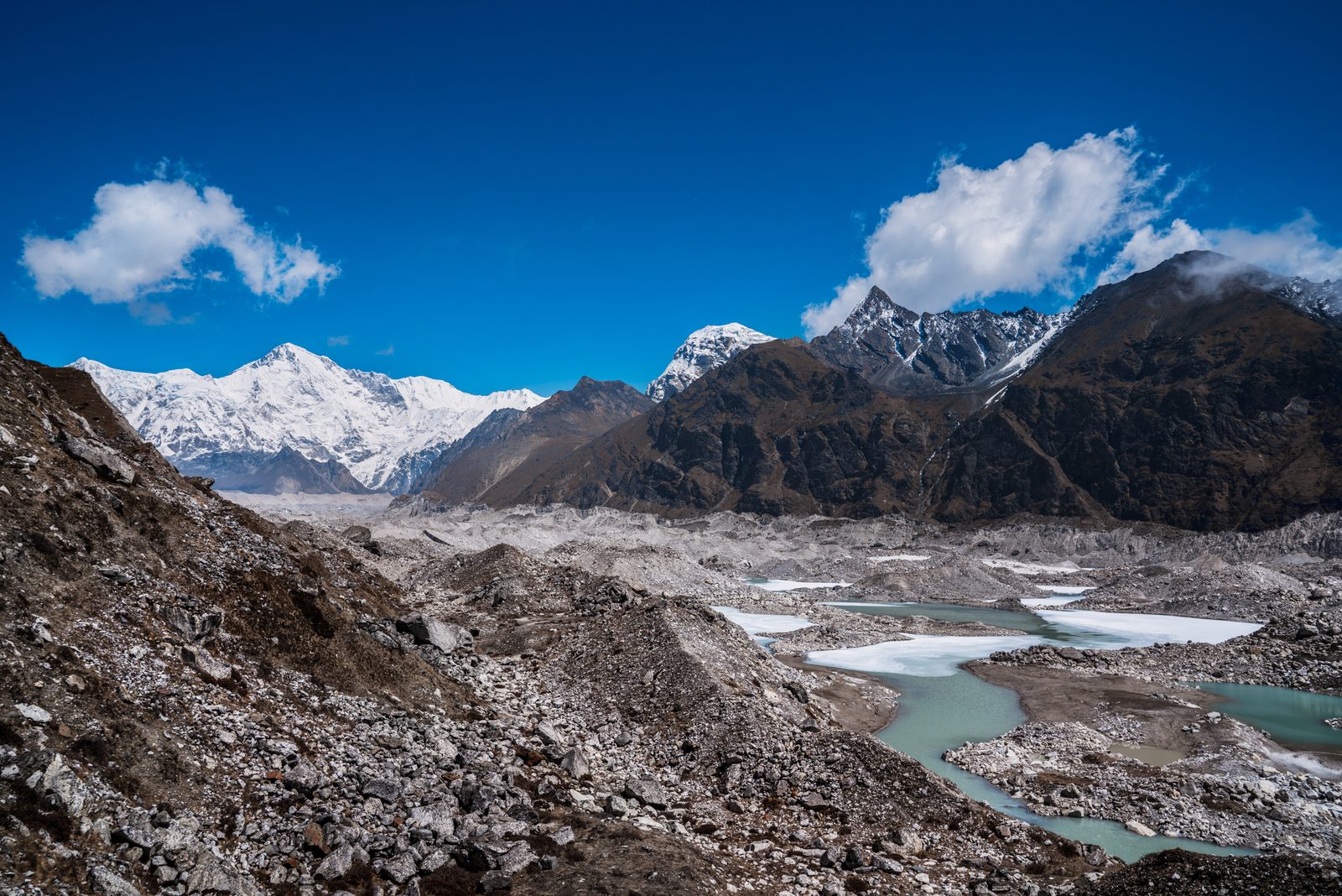 Melt pools on top of the Ngozumpa Glacier in Nepal's Himalayan region with Mt Choyo in the background