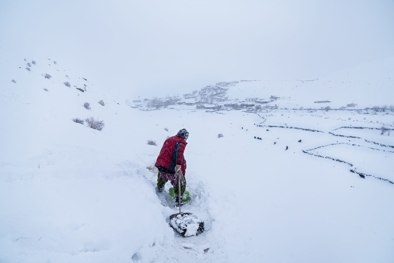 A woman pulls two 20-litre jerry cans of water down the mountainside towards Kumik