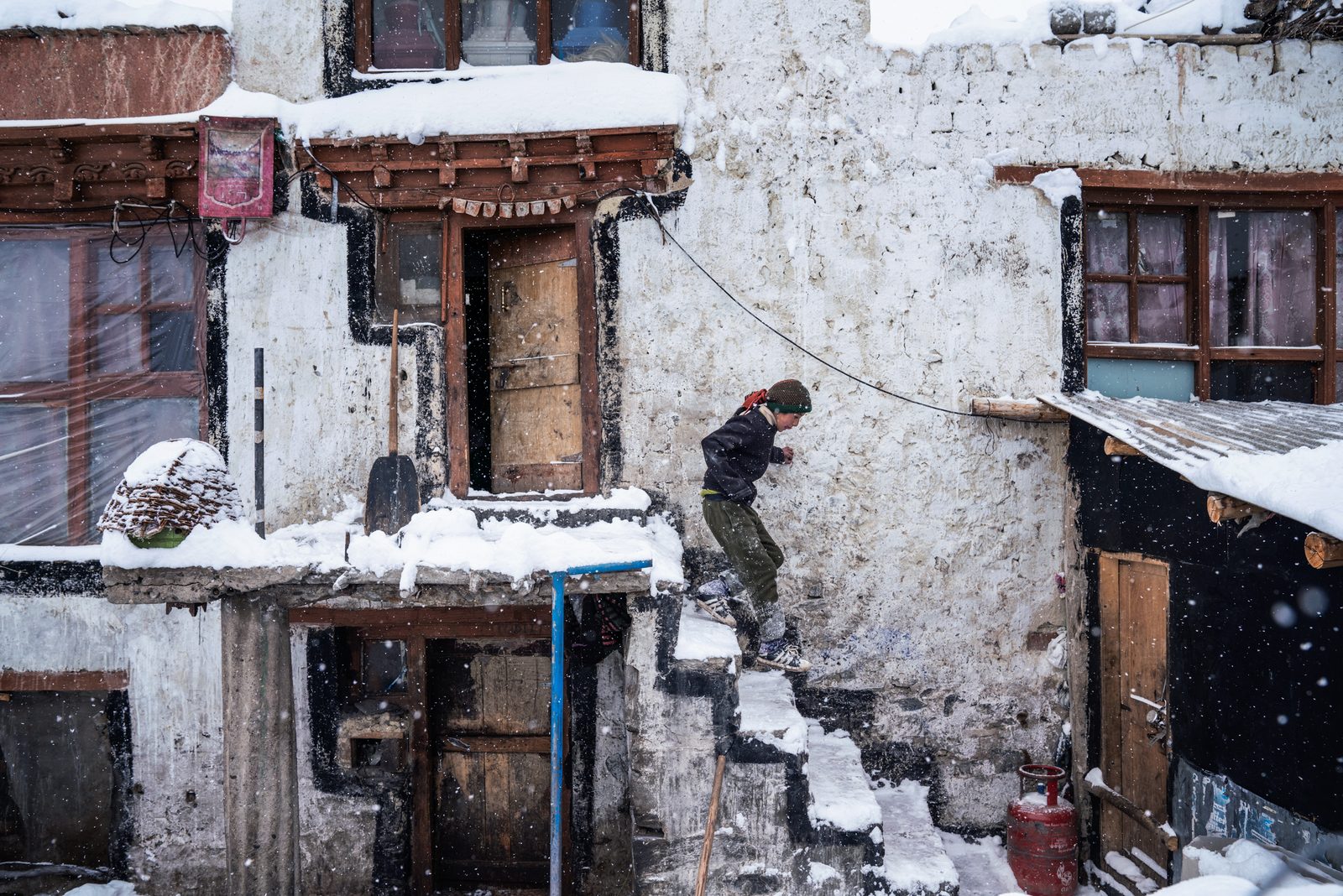 Tenzin Yangdoll rushes down the steps of her home to make sure the livestock are indoors before a blizzard hits
