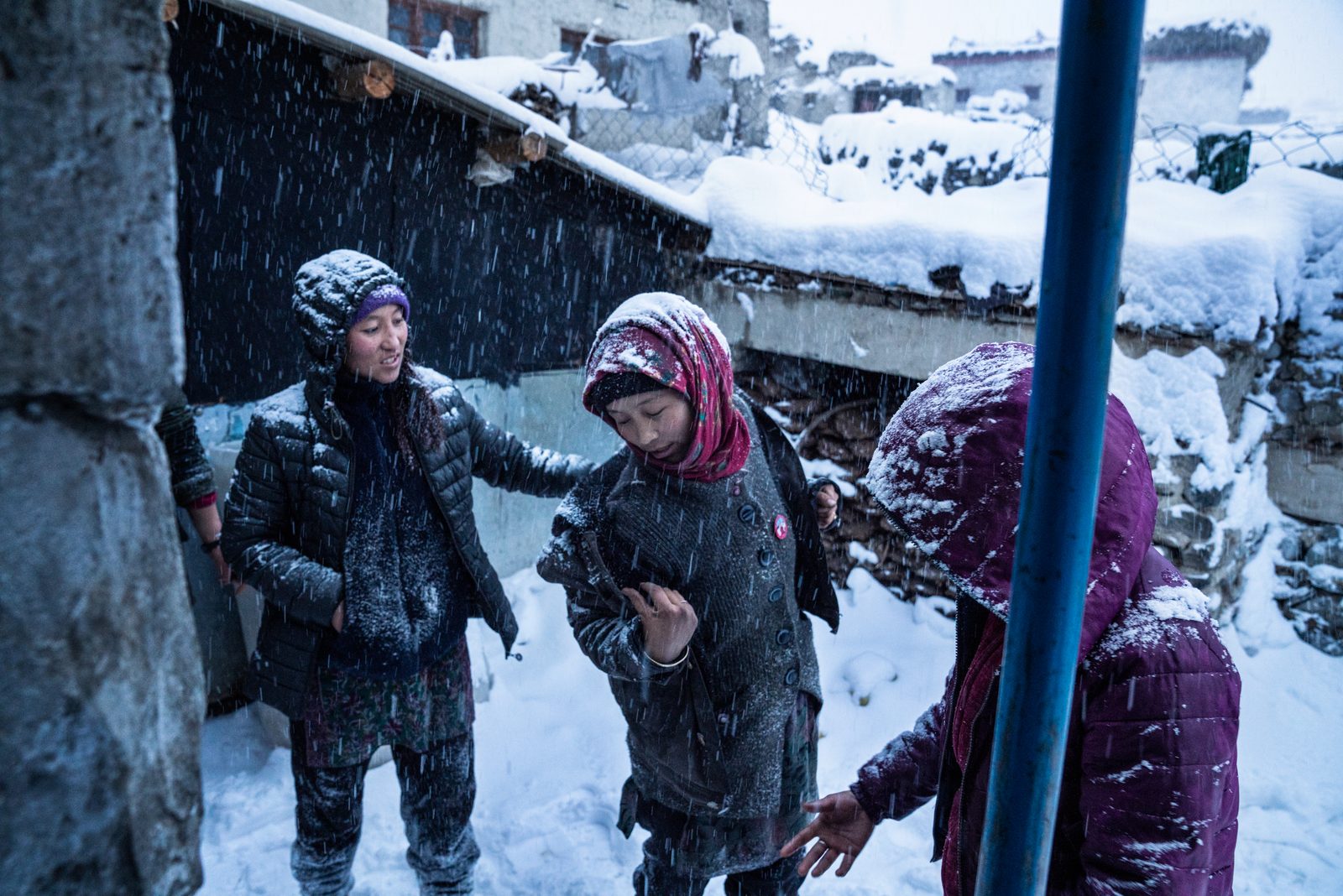 The younger women of Kumik wipe snow off each other durin a blizzard