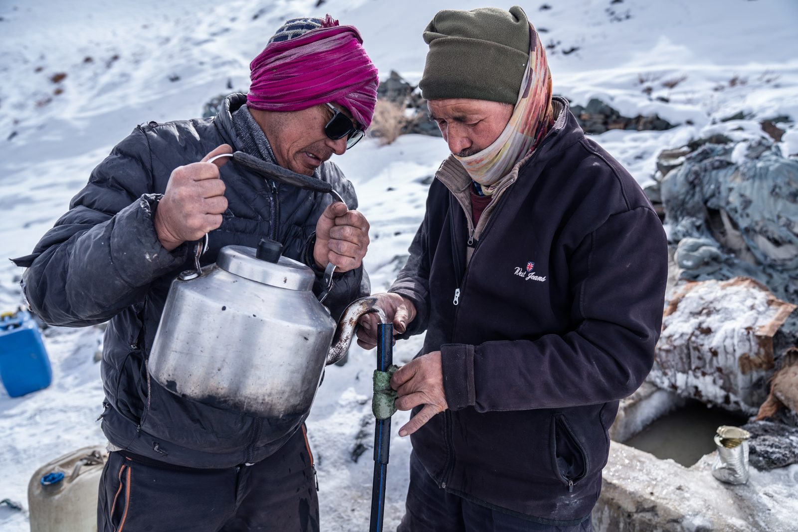 Tenzin Thinlay and another villager of Kumik pour boiling water down a pipe to dislodge ice and connect it to the spring