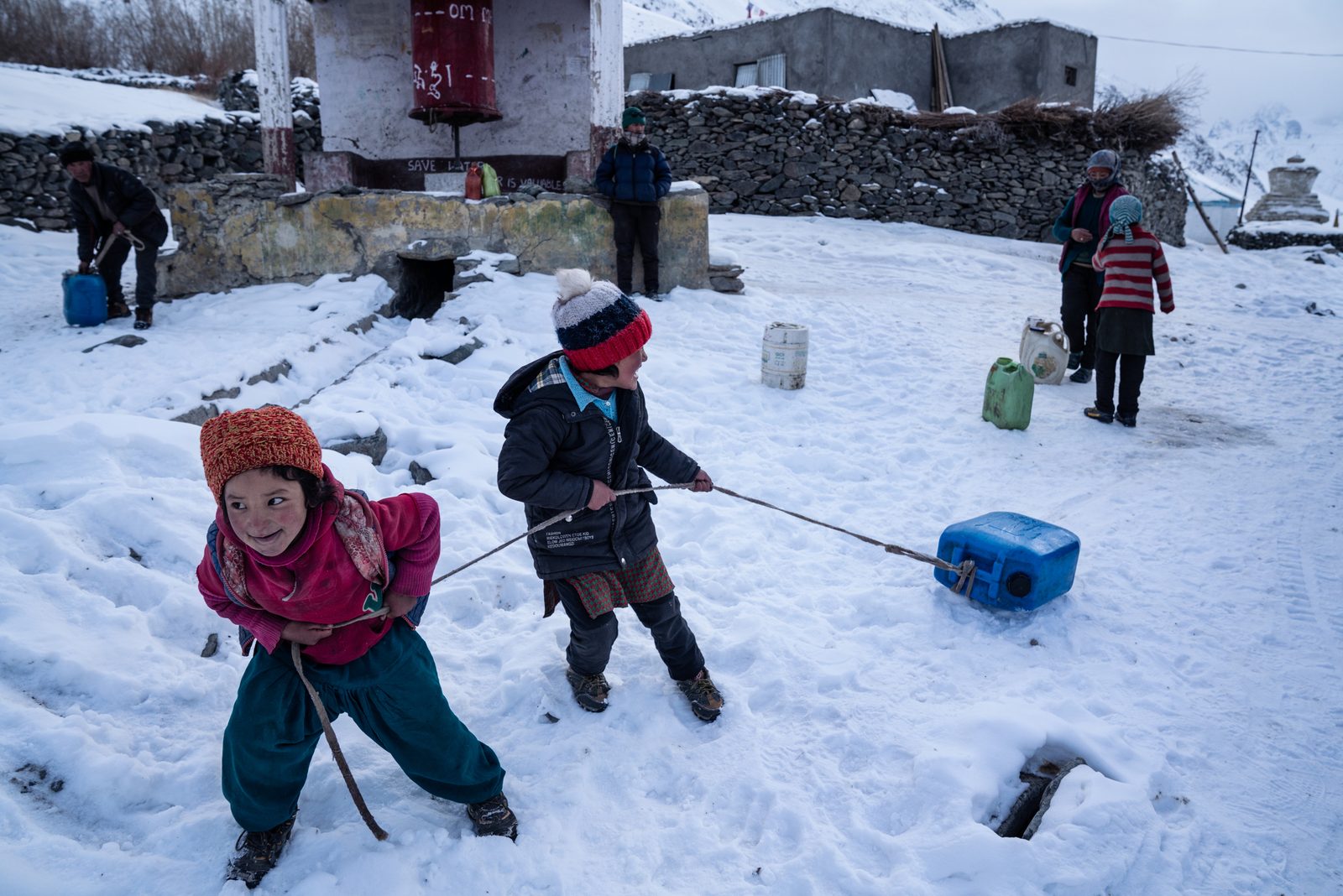 Children of Kumik drag jerry cans of water back to their homes