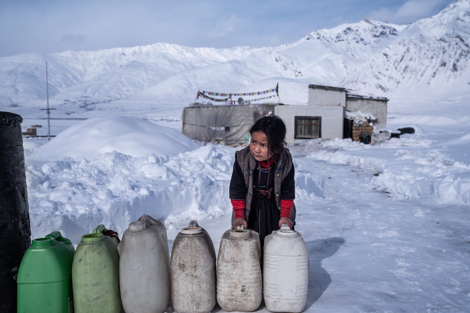 Tenzin K. of Lower Kumik waits for a government water tanker to arrive to fill up empty jerry cans