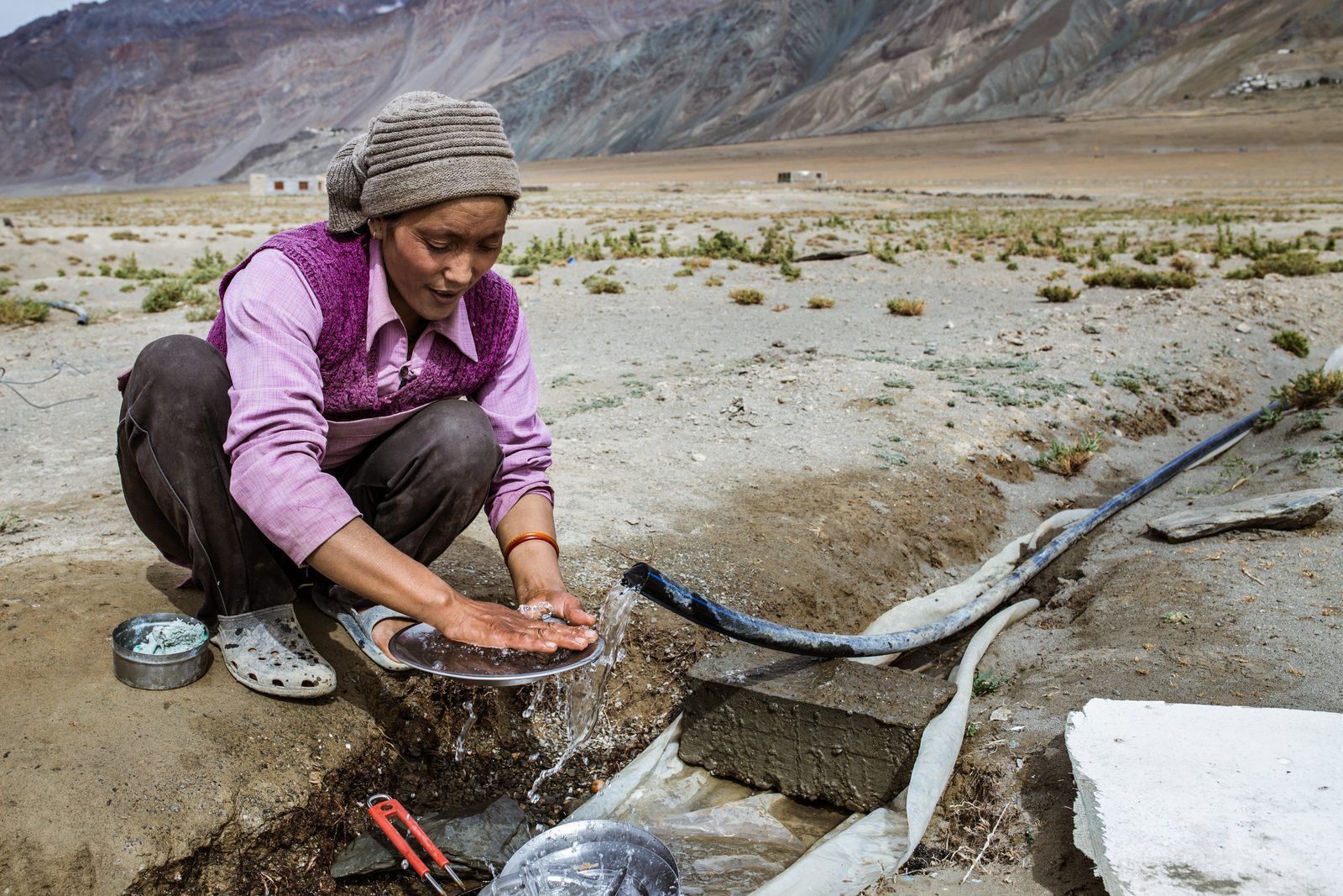 Thukjay Dolma washes her dishes outside in Lower Kumik