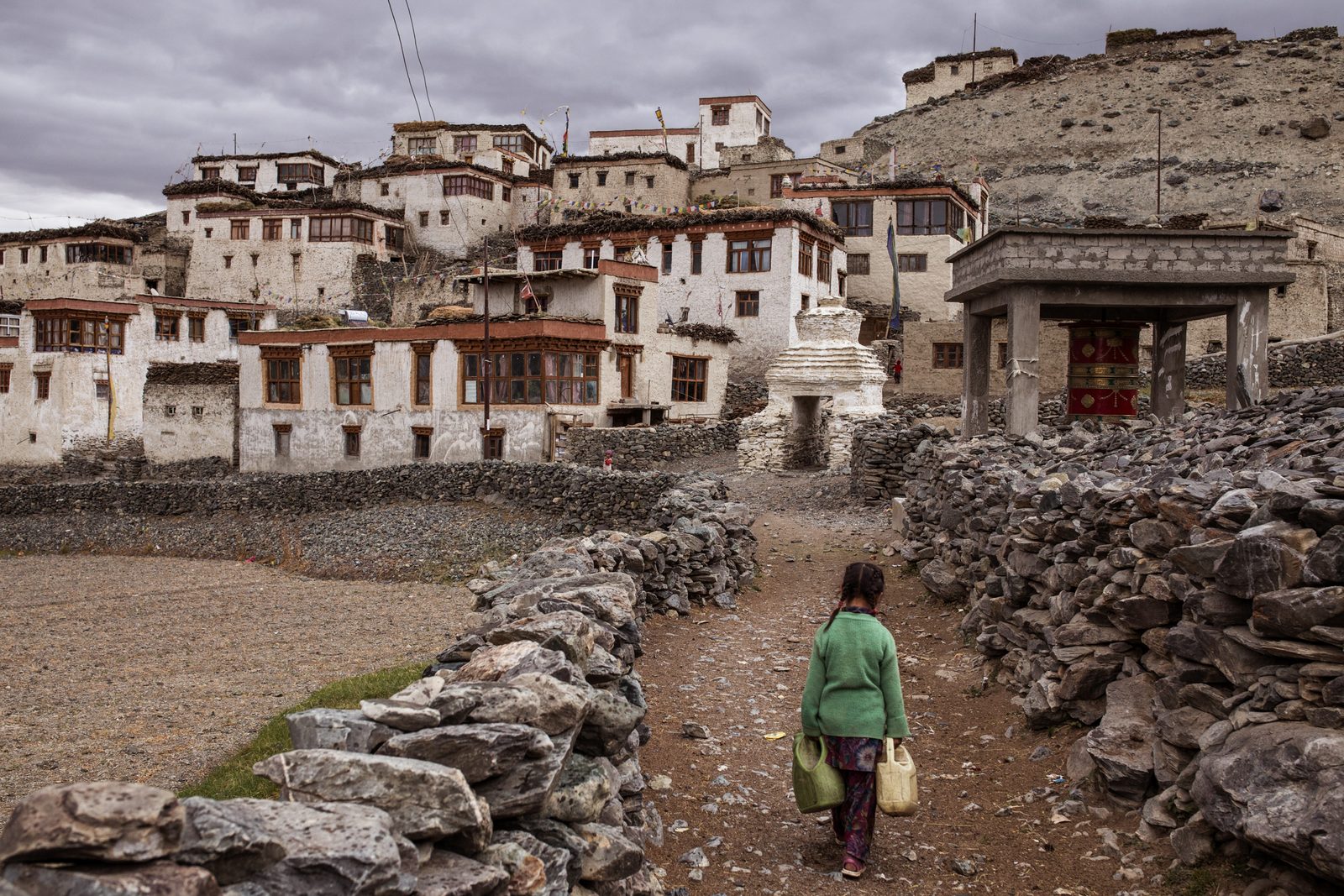 A child carries water from the canal back to her home in jerry cans